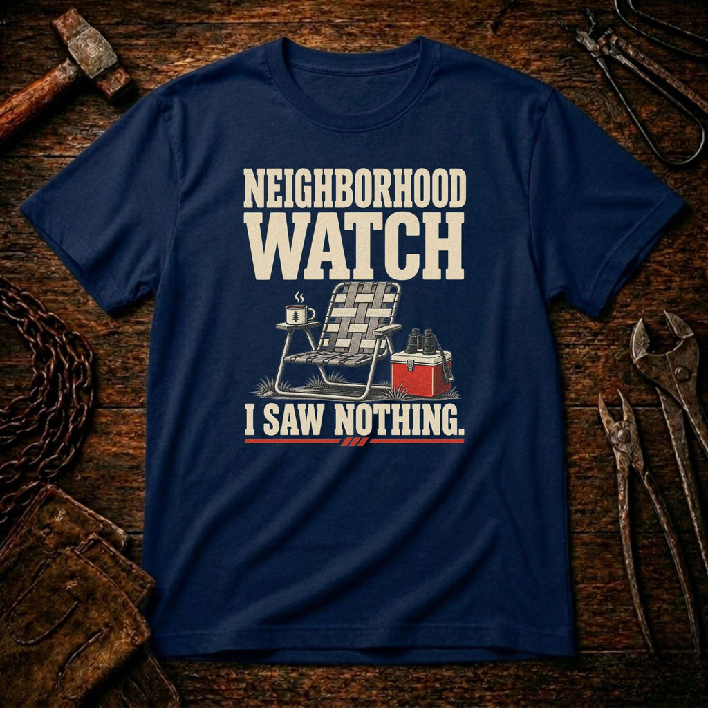 A navy blue graphic t-shirt laid flat on a rustic wooden background with tools like a hammer, wrenches, and a chain visible around it. The shirt features a graphic of a folding chair, a mug, and a red cooler with the text 'NEIGHBORHOOD WATCH I SAW NOTHING.