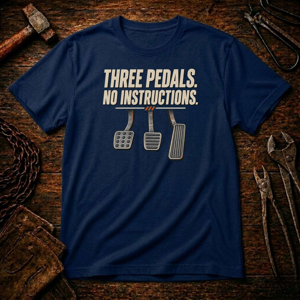 A navy blue crewneck t-shirt with a graphic print reading 'THREE PEDALS. NO INSTRUCTIONS.