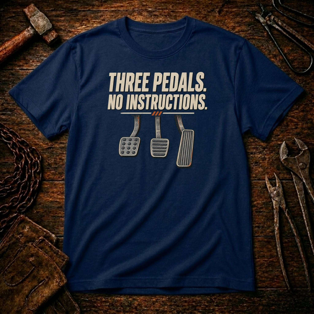 A navy blue crewneck t-shirt with a graphic print reading 'THREE PEDALS. NO INSTRUCTIONS.
