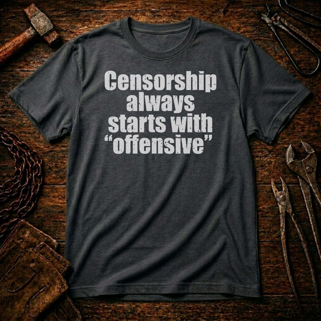 Gray t-shirt with text 'Censorship always starts with offensive' on a rustic wooden background.