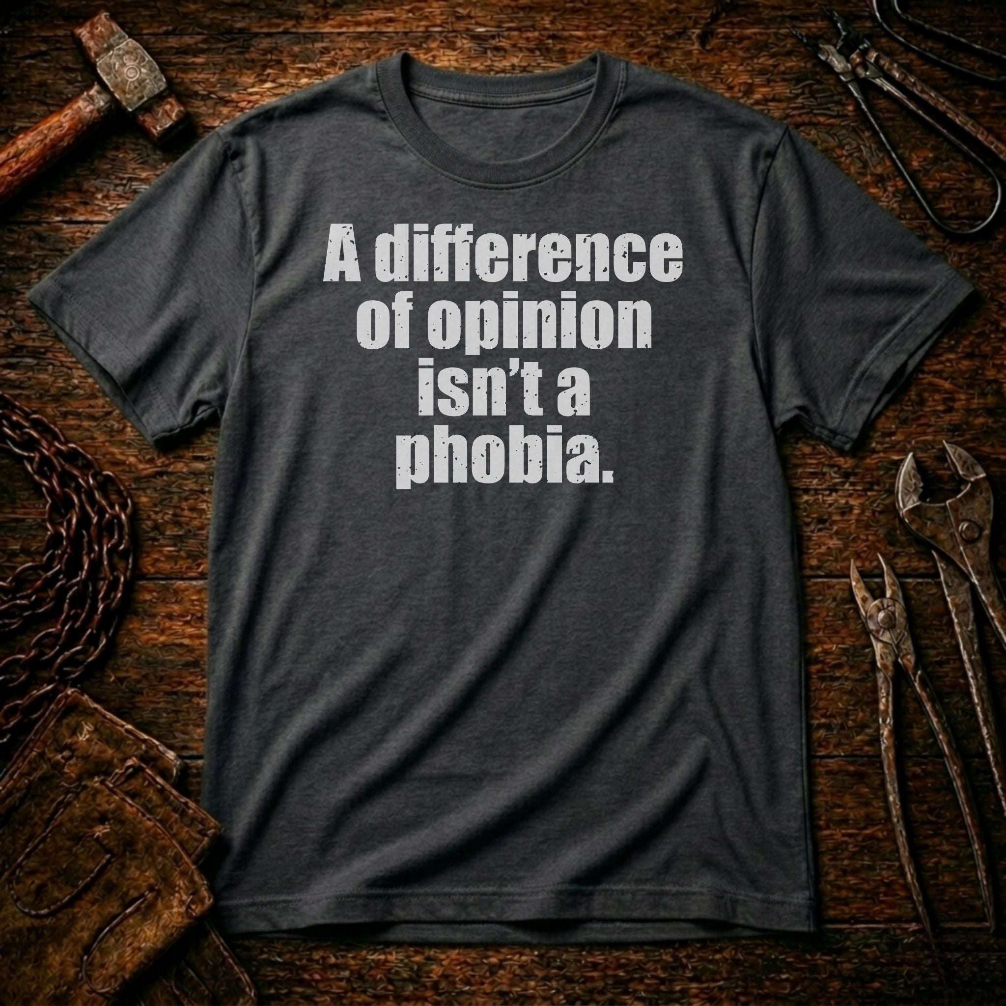 Gray t-shirt with text 'A difference of opinion isn't a phobia' on a rustic wooden background.